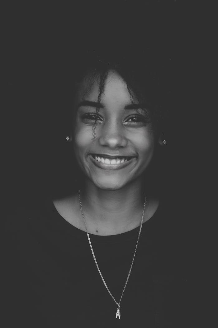 Black and white portrait of a smiling woman showcasing elegance and beauty.