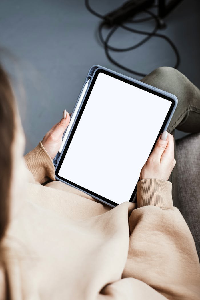 A person holding a tablet with a blank screen, ideal for mockups and presentations.