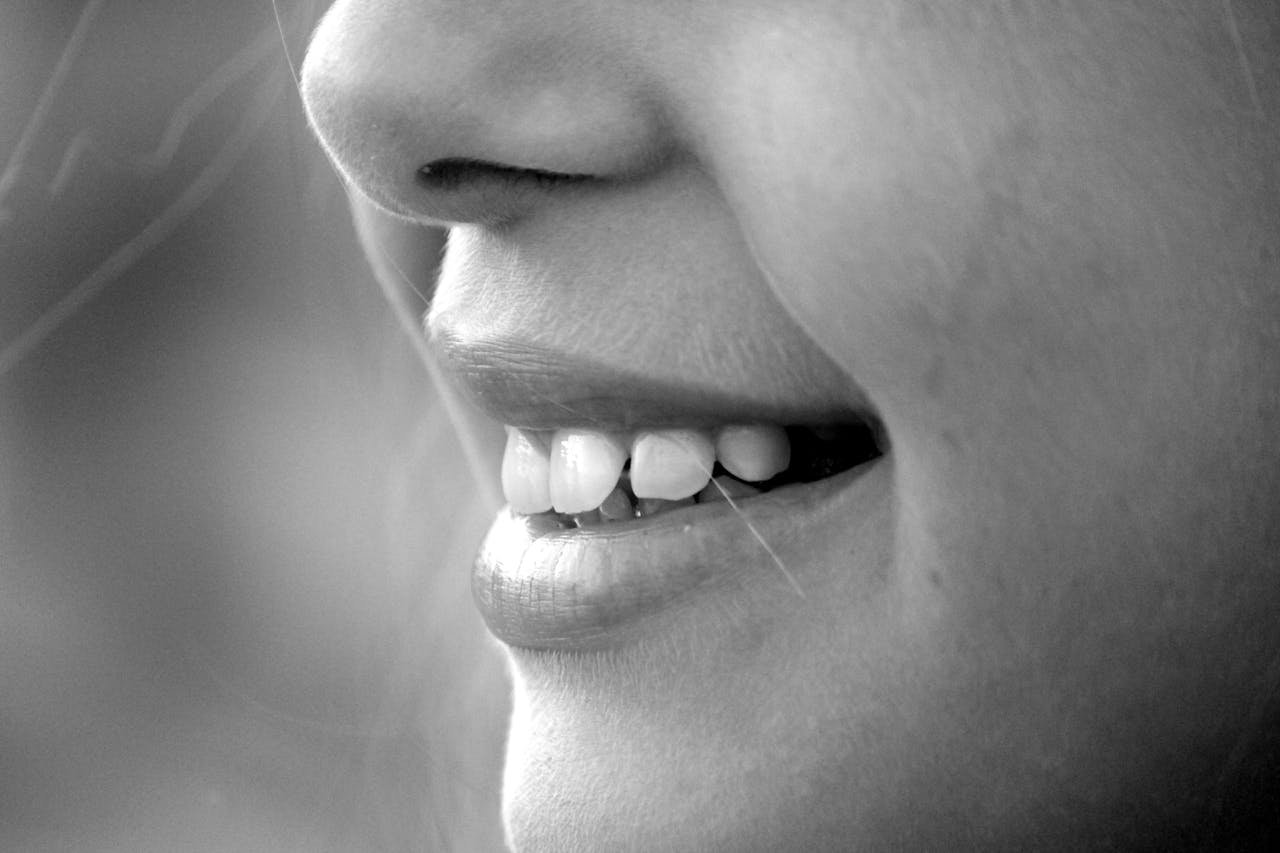 why-choose-us A monochrome close-up of a smiling face showcasing teeth and lips.